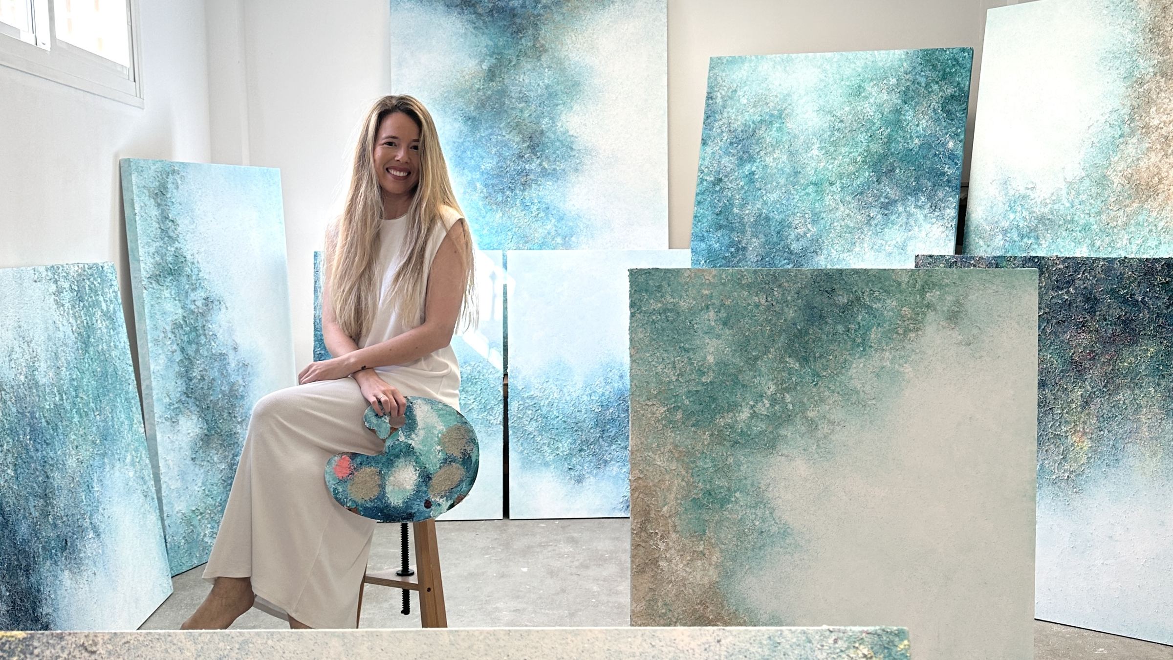 Tania Ciffer en su estudio, sentada entre sus cuadros en tonos azules